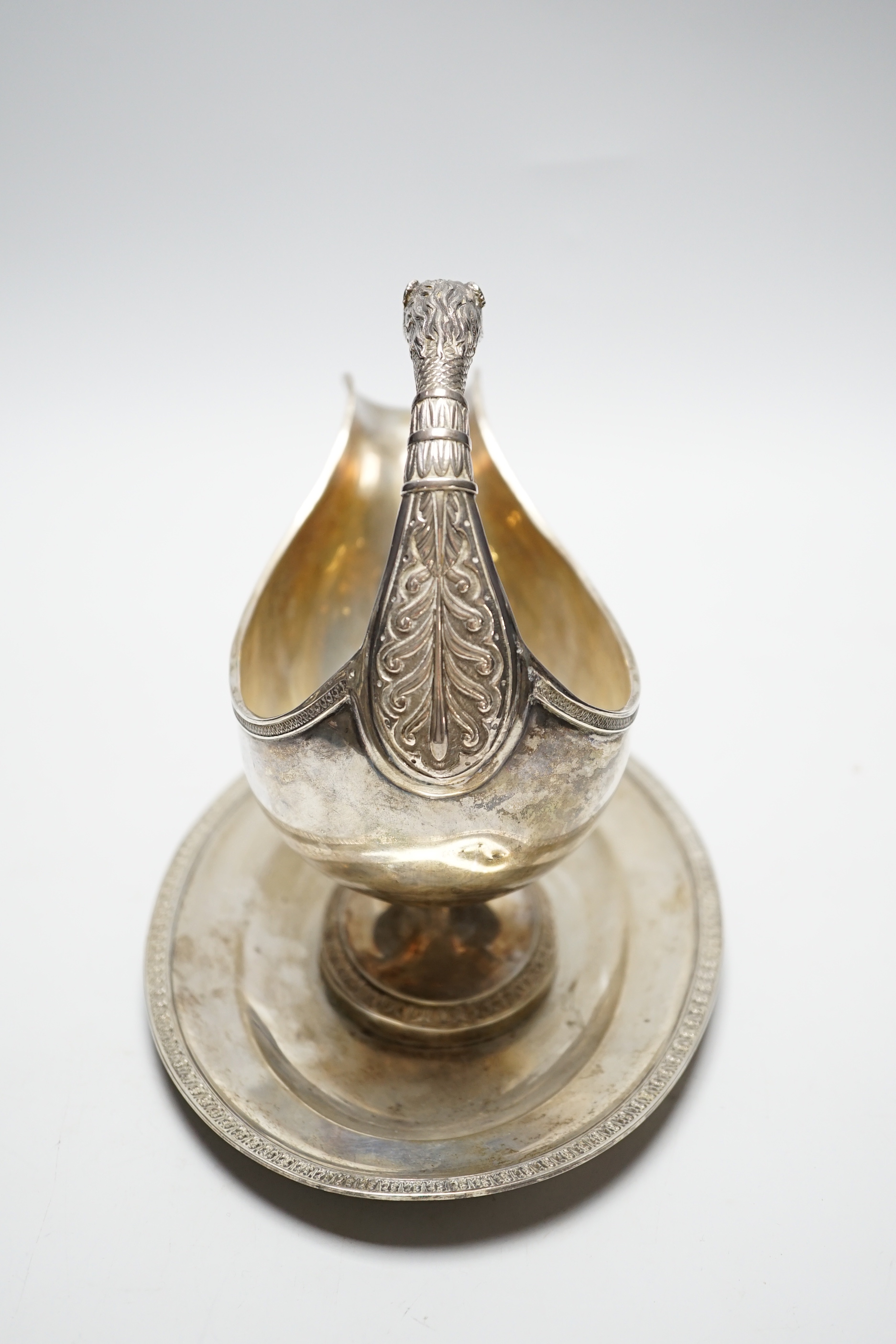 A continental white metal sauceboat on stand, with flying scroll leopard's head handle, length 23.8cm, 24.7oz.